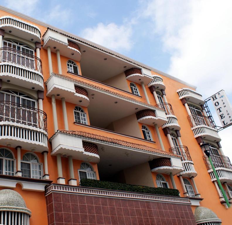 比亚埃尔莫萨Hotel San Juan Centro的一座橙色的建筑,设有阳台和钟表