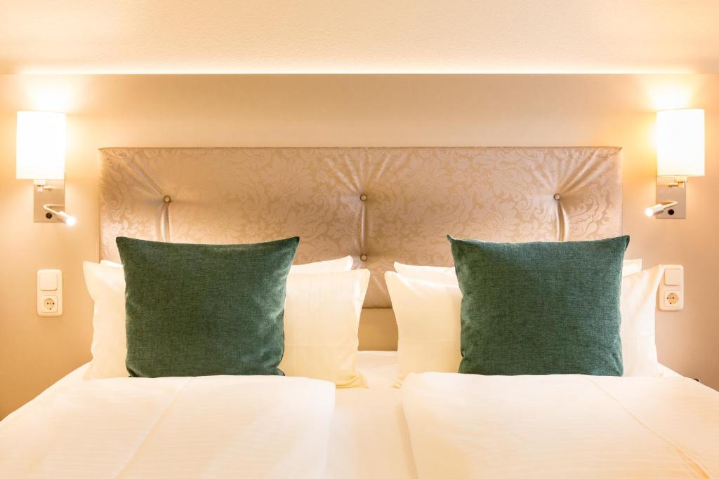 奥尔登堡奥尔登堡赫耳墨斯酒店的卧室配有白色床和2个绿色枕头