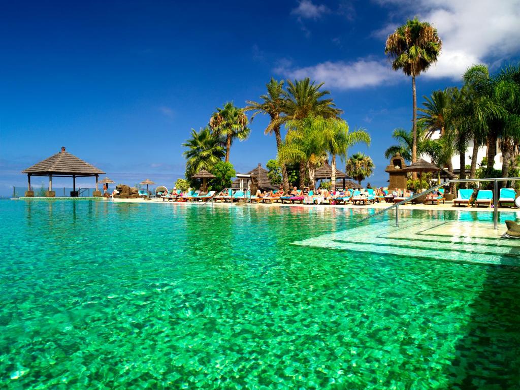 美洲海滩丽晶乡村俱乐部酒店的一座拥有绿松石水和棕榈树的游泳池