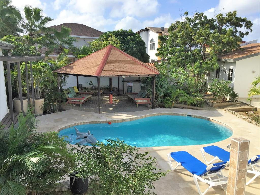 棕榈滩鹦鹉别墅酒店的一个带两把椅子的游泳池和一个凉亭