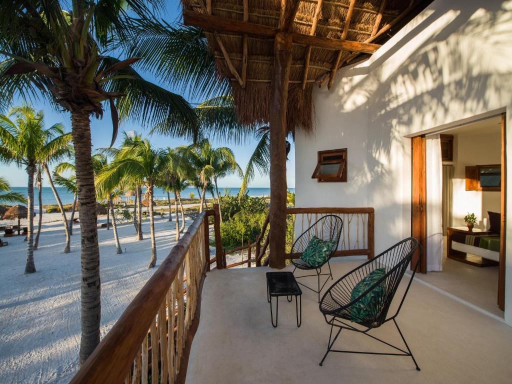奥尔沃克斯岛Villas HM Palapas del Mar的海滩上带椅子和棕榈树的阳台