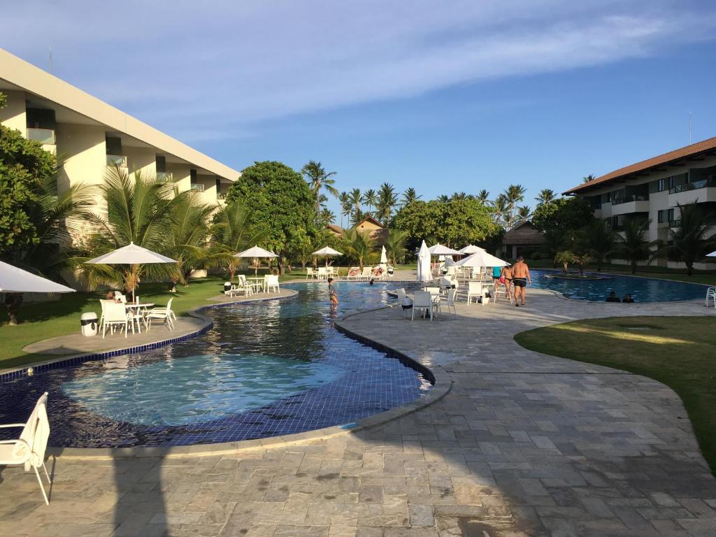 塔曼达雷Carneiros Beach Resort的一个带桌椅的游泳池的度假酒店