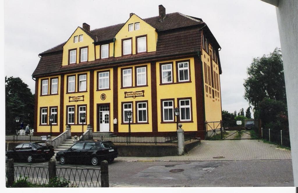 卑尔根格塞施法兹酒店的一座黄色的建筑,前面停有两辆车