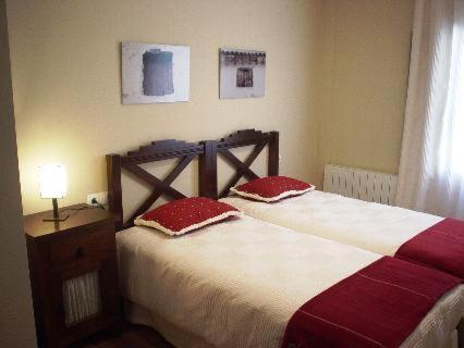 贝尔蒙特Casa Rural Descanso del Quijote的一间卧室配有一张带两个红色枕头的床