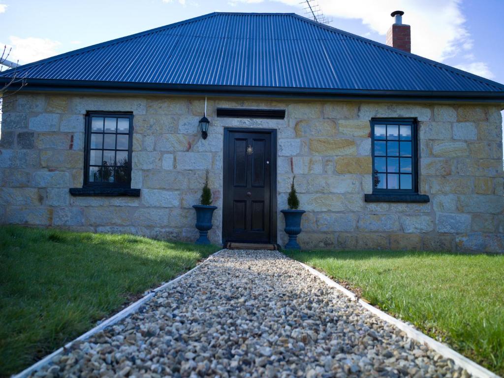 Buckland斯特奥瑞克皮尔斯别墅的一座石头房子,设有黑色的门和两扇窗户