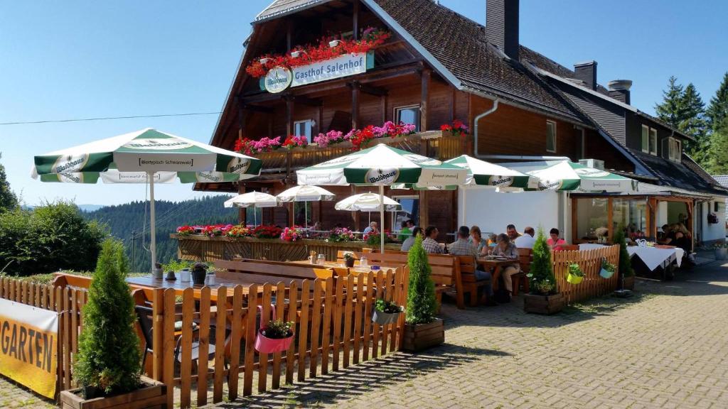 蒂蒂湖-新城Schwarzwaldgasthaus Salenhof的大楼前的餐厅,配有桌子和遮阳伞