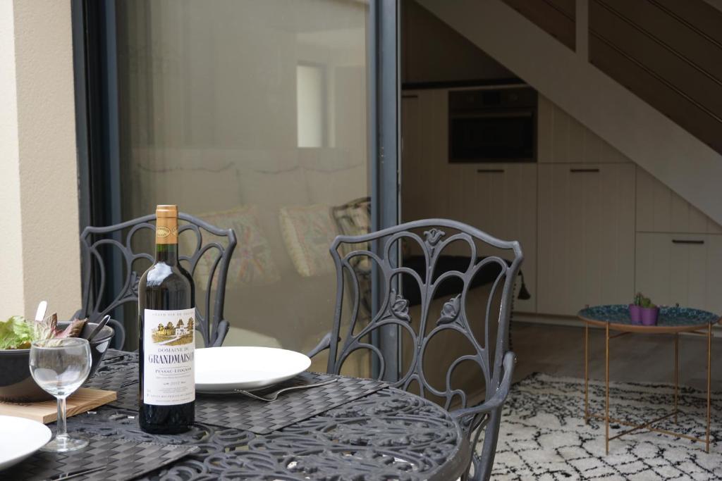 波尔多La Villa Verte的桌椅上摆放着一瓶葡萄酒