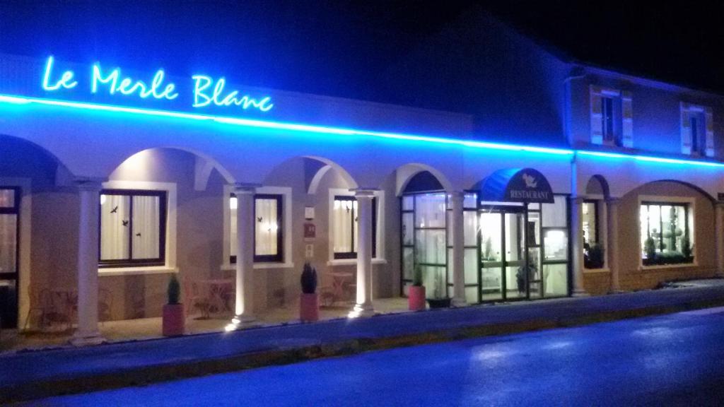 迪关Le Merle Blanc Hôtel Logis的上面有蓝色 ⁇ 虹灯标志的建筑