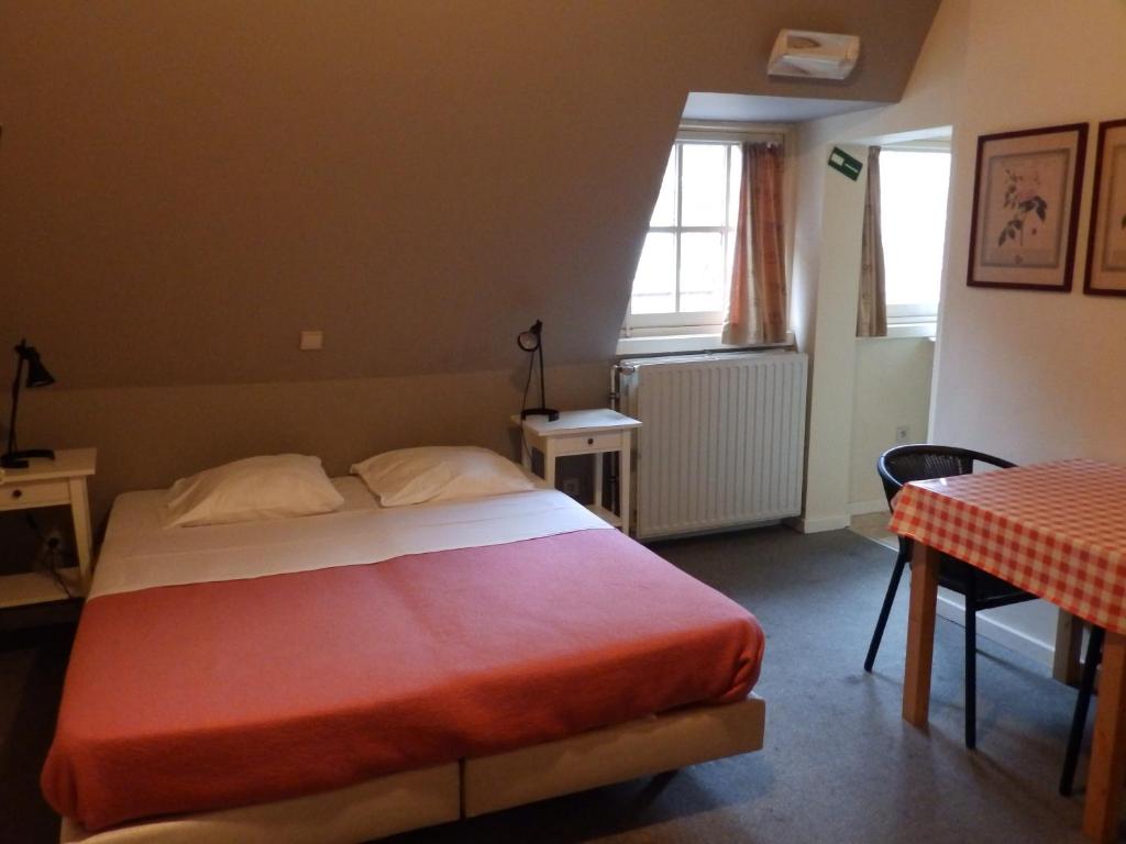 米德尔克尔克Logies De Wandelaar的一间卧室配有一张床、一张桌子和一个窗户。
