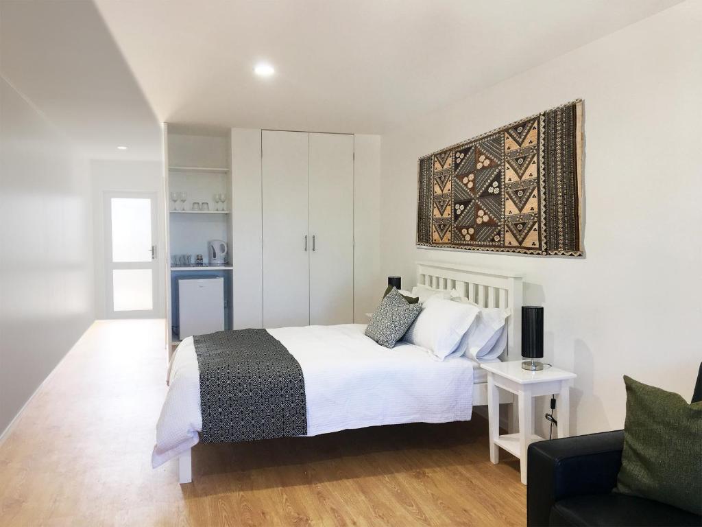 努库阿洛法汤加之家酒店的卧室配有白色的床和沙发