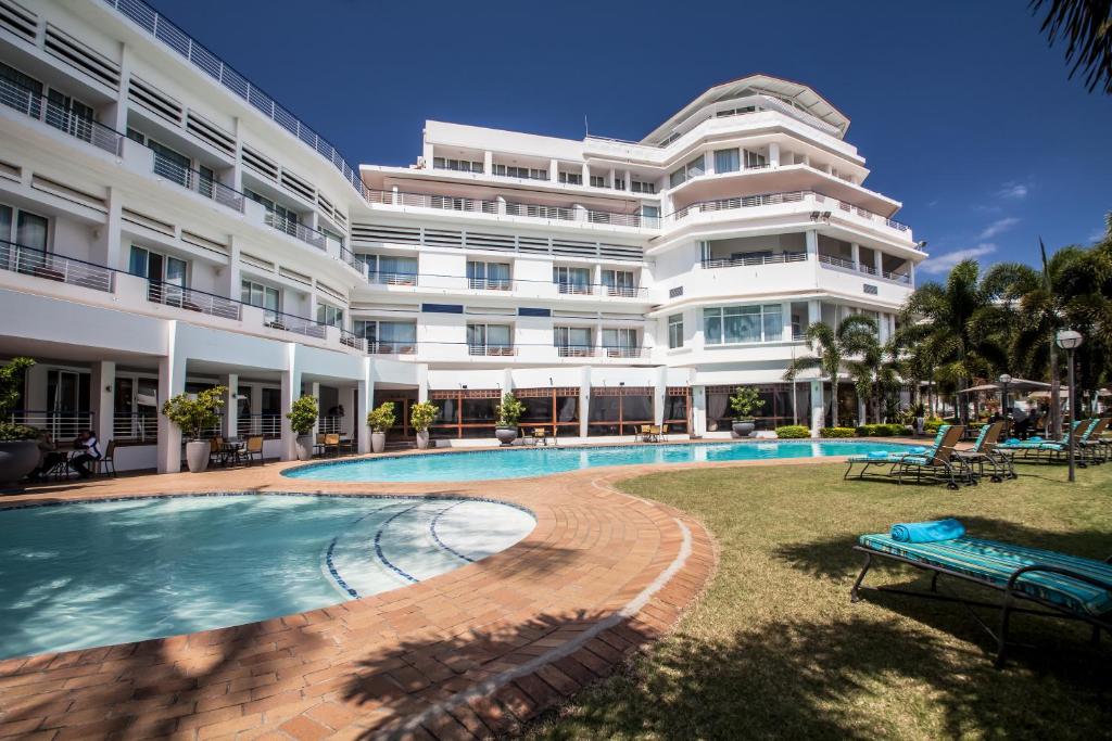 马普托卡多佐酒店的一座白色的大建筑,前面设有一个游泳池