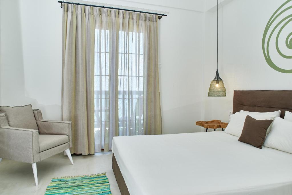 阿吉奥斯伊欧尼斯Kelly Hotel Agios Ioannis Pelion的卧室配有一张白色大床和一把椅子