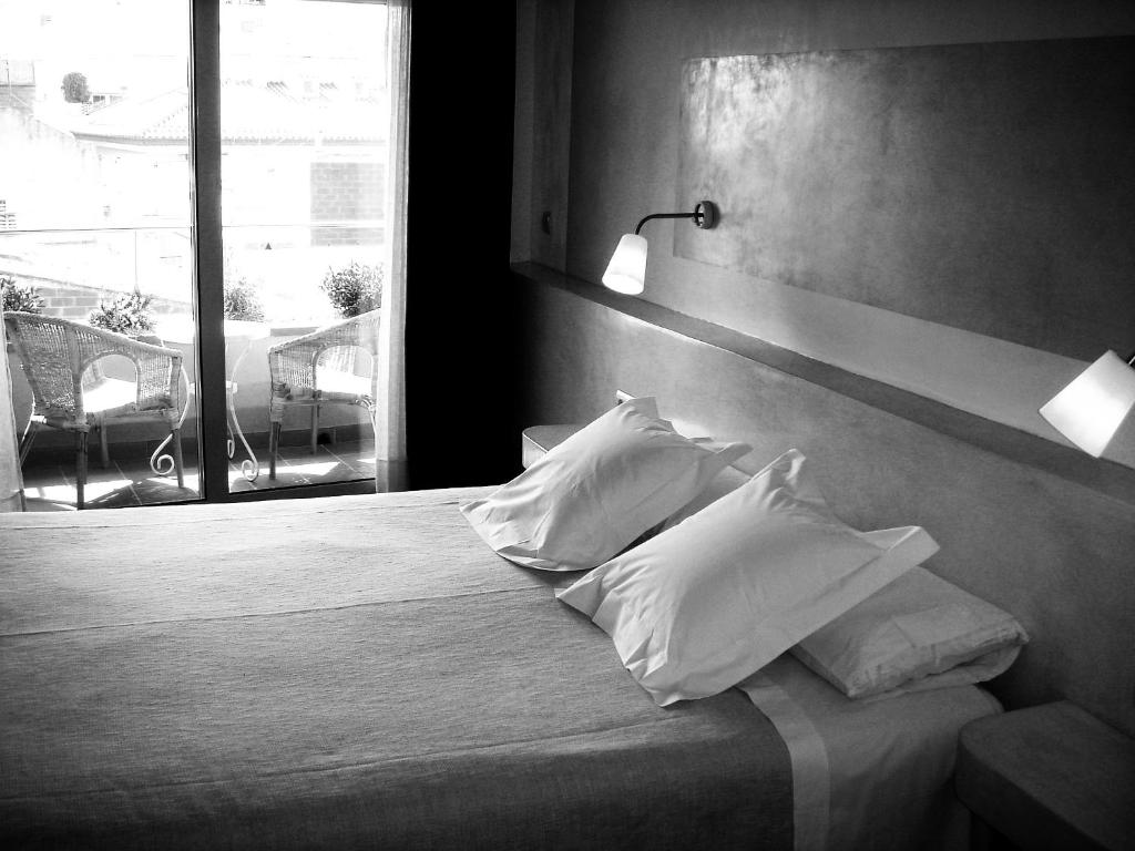 罗萨斯卡门酒店的卧室配有带枕头的床铺和窗户。
