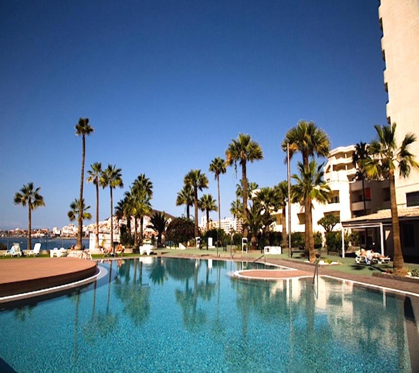 洛斯克里斯蒂亚诺斯Amazing sea view in Los Cristianos的一座棕榈树大型游泳池和一座建筑