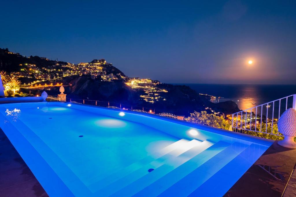 陶尔米纳斯恰克萨住宿加早餐旅馆的游泳池,晚上可欣赏到海景