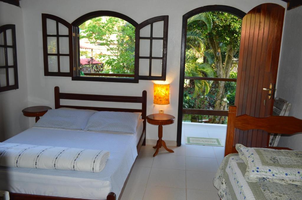 阿布拉奥Recanto das Flores Lofts - Ilha Grande Rj的一间卧室设有一张床和两个窗户。