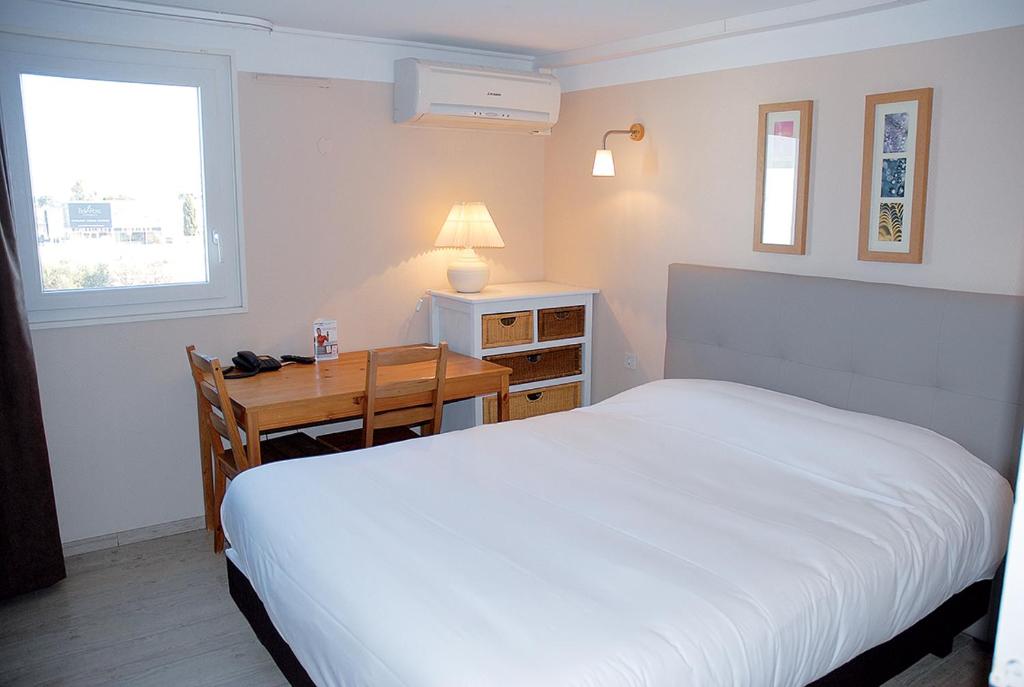 莫吉奥Contact Hotel LE SUD Montpellier Aéroport Parc Expo Arena的卧室配有白色的床和带台灯的书桌