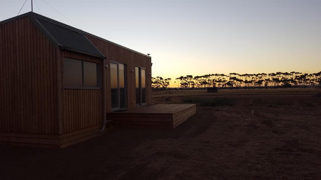 Lara拉拉小屋住宿加早餐旅馆的一座小建筑,设有门廊,背面是日落