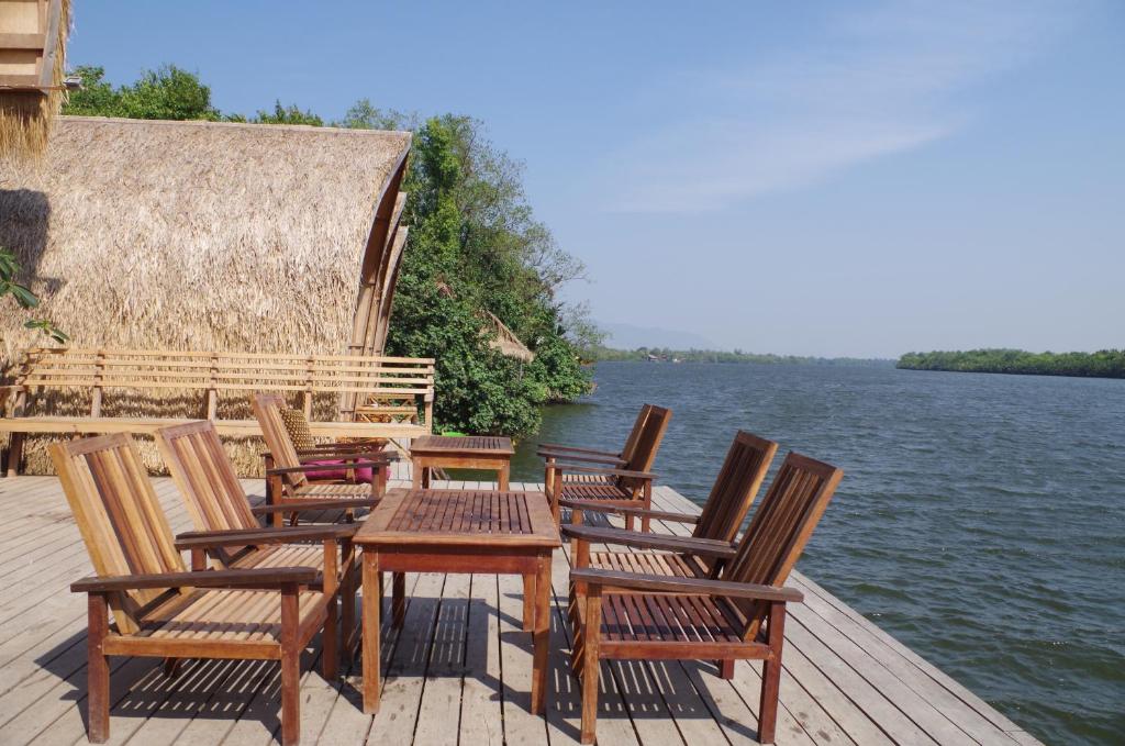 贡布竹制简易别墅度假村的一组椅子和一张桌子,放在水边的码头上