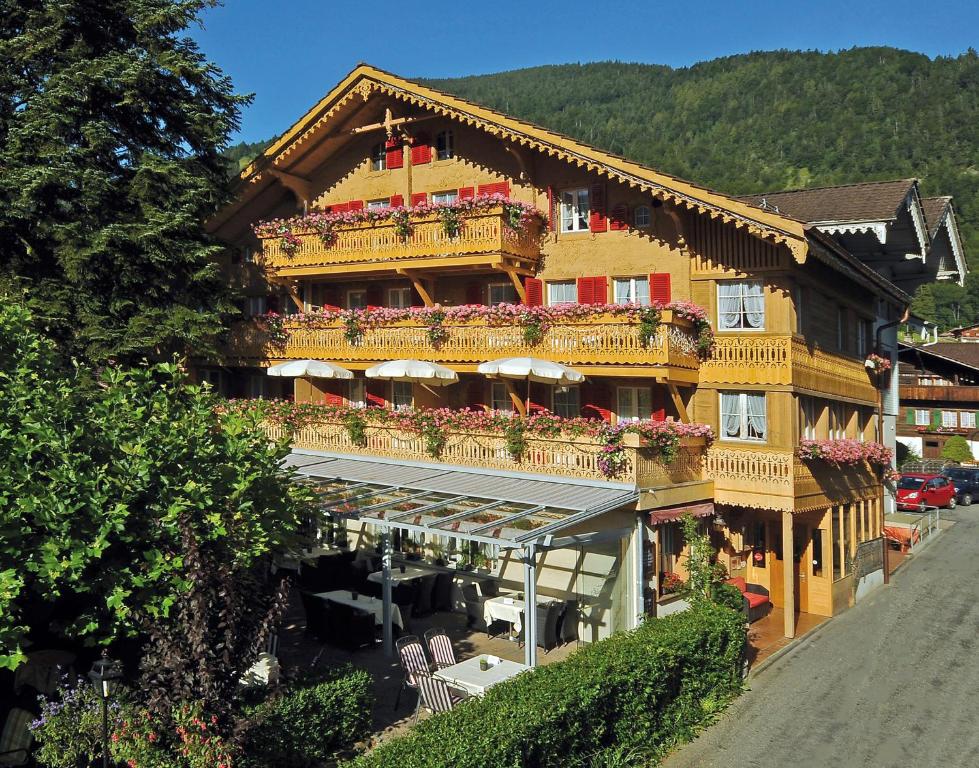 维尔德斯韦尔Alpenblick Hotel & Restaurant Wilderswil by Interlaken的一座带阳台的大型建筑,鲜花盛开
