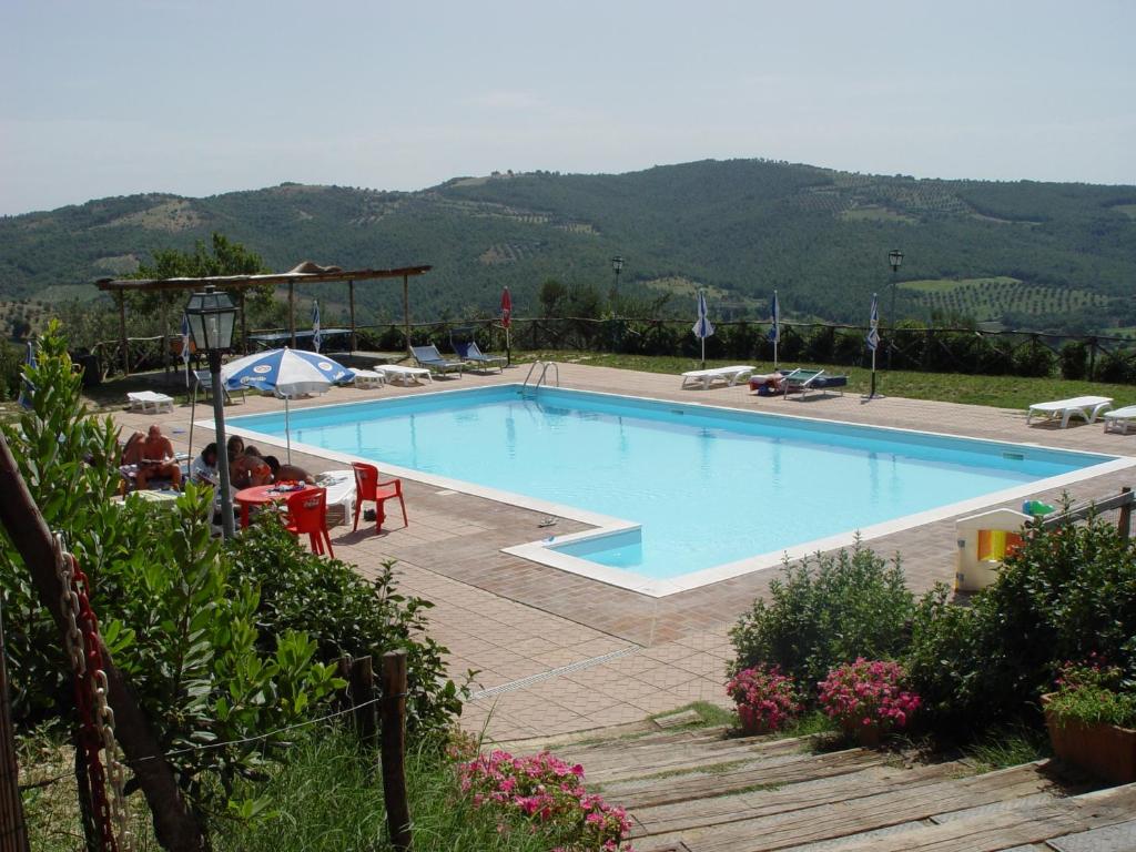 特拉西梅诺湖畔帕西尼亚诺Casale Poggio Colpiccione的一座大游泳池,后面是一座山