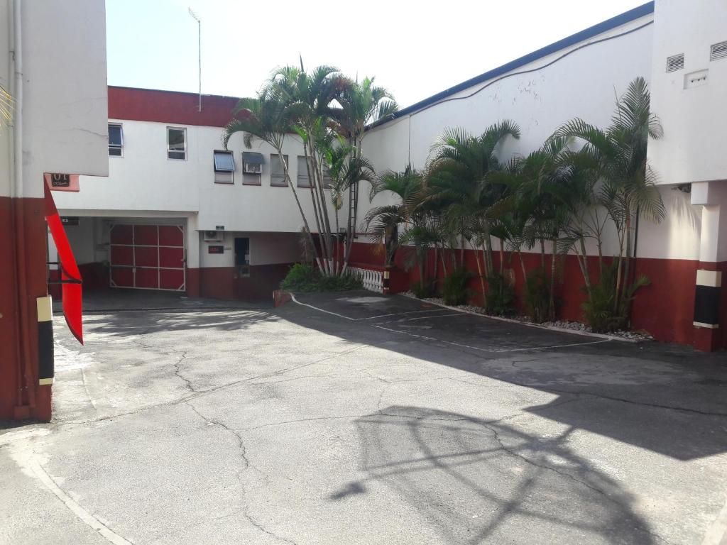 圣保罗Motel Sedução的棕榈树建筑前的停车场
