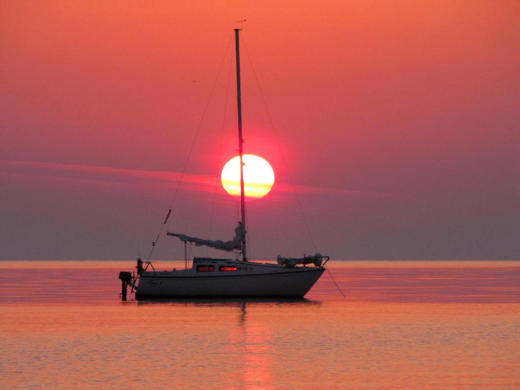 普里恩斯慕斯Beachside Guest House Strautini的水中的小船,背景是日落
