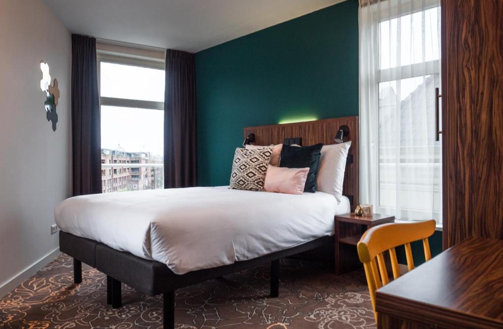 阿姆斯特丹林登酒店的一间卧室设有一张大床和绿色的墙壁