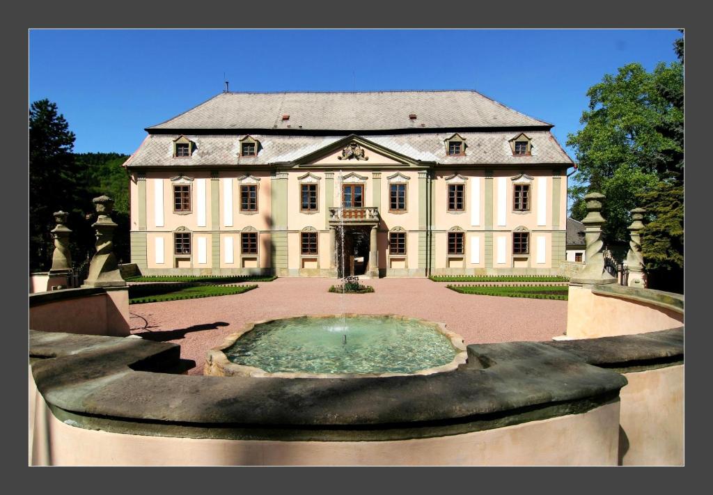 Potštejn波西坦堡酒店的一座白色的大房子,前面有一个喷泉