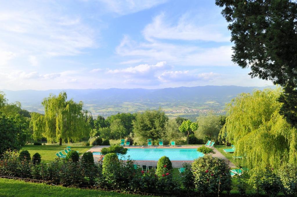 维基奥维拉坎佩斯特里橄榄油度假酒店的花园中的一个游泳池,花园内种有树木和山脉