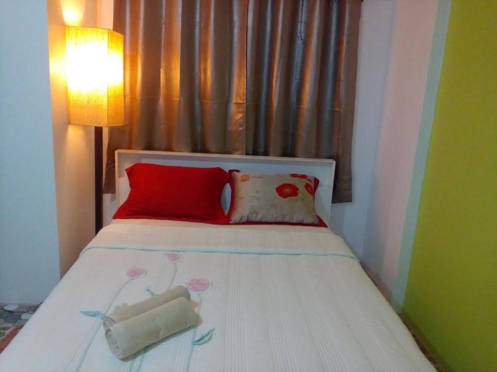 暖武里府乌萨拜旅馆的一间卧室配有红色枕头的床