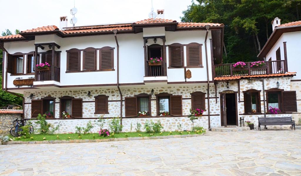 Rozhen丁科瓦库什塔家庭酒店的白色的房子,有棕色百叶窗和长凳