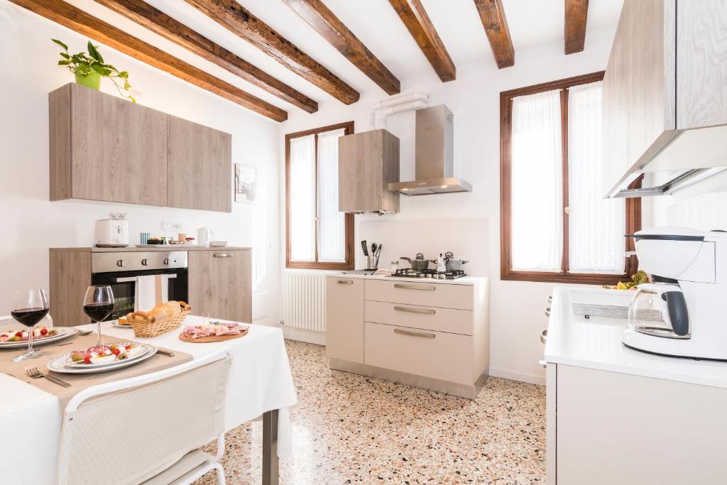 威尼斯Cà Boldo Terrace 2.0的厨房配有白色橱柜和一张带食物的桌子。