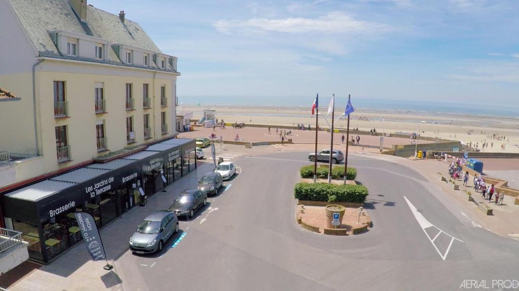 马翁普拉日堡特拉斯酒店的一条街道,旁边是一座建筑和海滩,有汽车停放