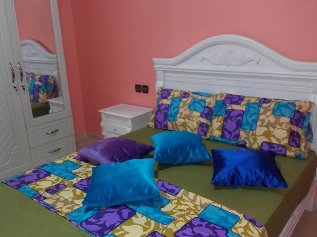 盖尼特拉Bienvenue chez vous的一间卧室配有一张带蓝色和紫色枕头的床