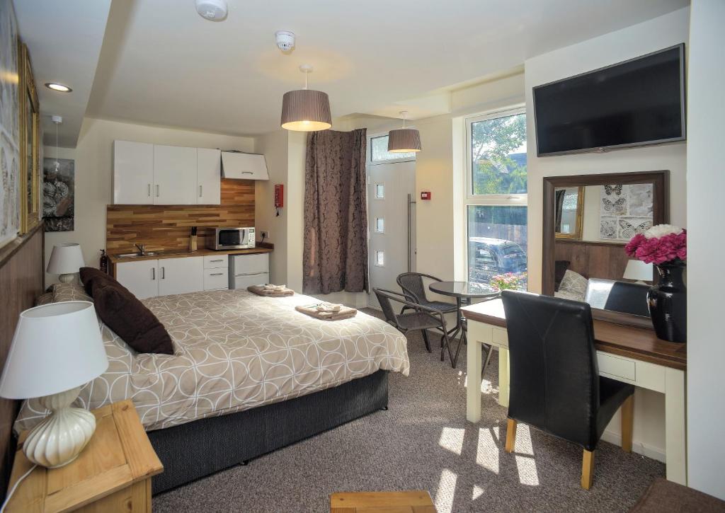 诺里奇Riverside Hotel的一间带一张床和一张书桌的卧室和一间厨房