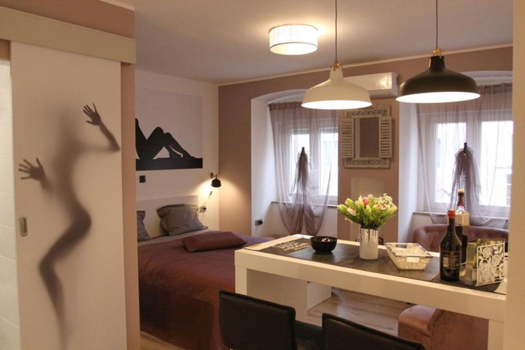 里耶卡Apartment Mala tajna的一间卧室配有一张床和一张桌子及一瓶葡萄酒