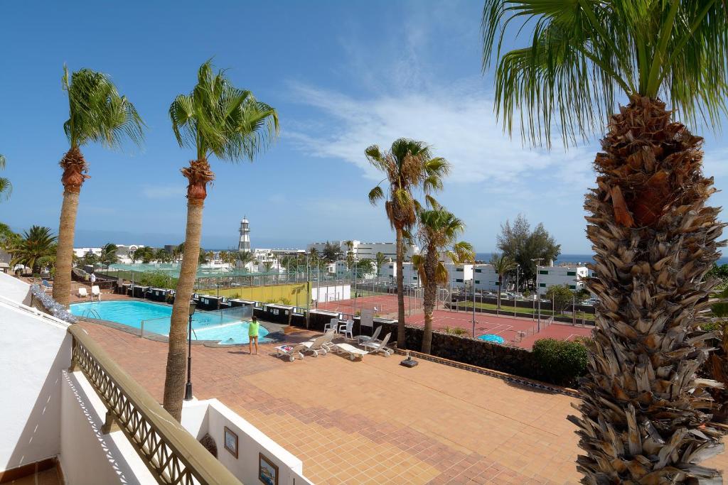 卡门港Playa Grande Puerto del Carmen Share Pool By PVL的一个带棕榈树和游泳池的阳台
