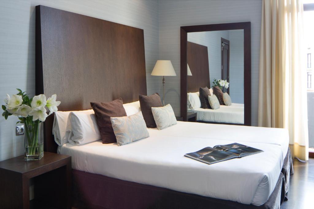 巴塞罗那Hotel Ramblas Internacional的酒店客房设有一张带镜子的大型白色床