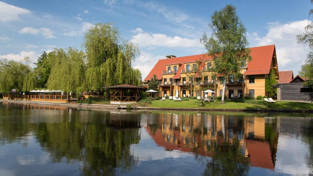 吕本斯特兰豪斯酒店 - 精品SPA度假酒店的一座树成荫的水体旁边的建筑
