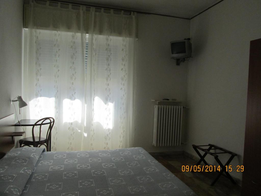 因佩里亚Pensione Aurora的一间卧室设有一张床、一个窗口和一台电视