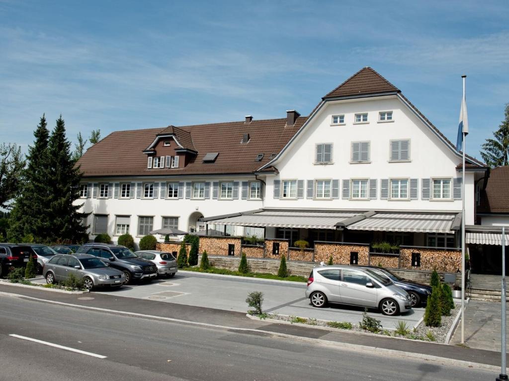 皮勒恩盖斯特豪斯迪艾珀尔酒店的一座白色的大建筑,汽车停在停车场