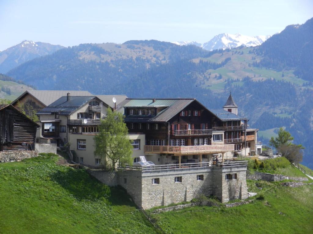 Wergenstein魔羯酒店餐厅的山丘上一座大房子,背景是群山