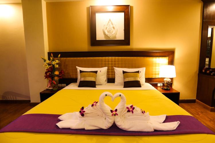 罗勇麦地那罗勇酒店的两个天鹅,看起来像个心,坐在床上