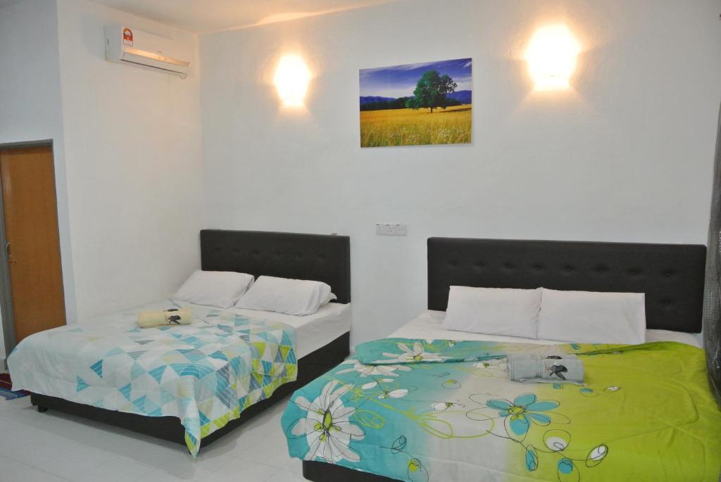 珍南海滩兰卡威波浪宾馆的卧室配有两张床,墙上挂着一幅画