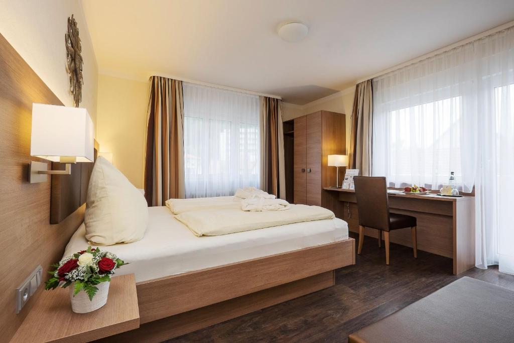 绍普夫海姆Hotel-Gasthaus Adler的配有一张床和一张书桌的酒店客房