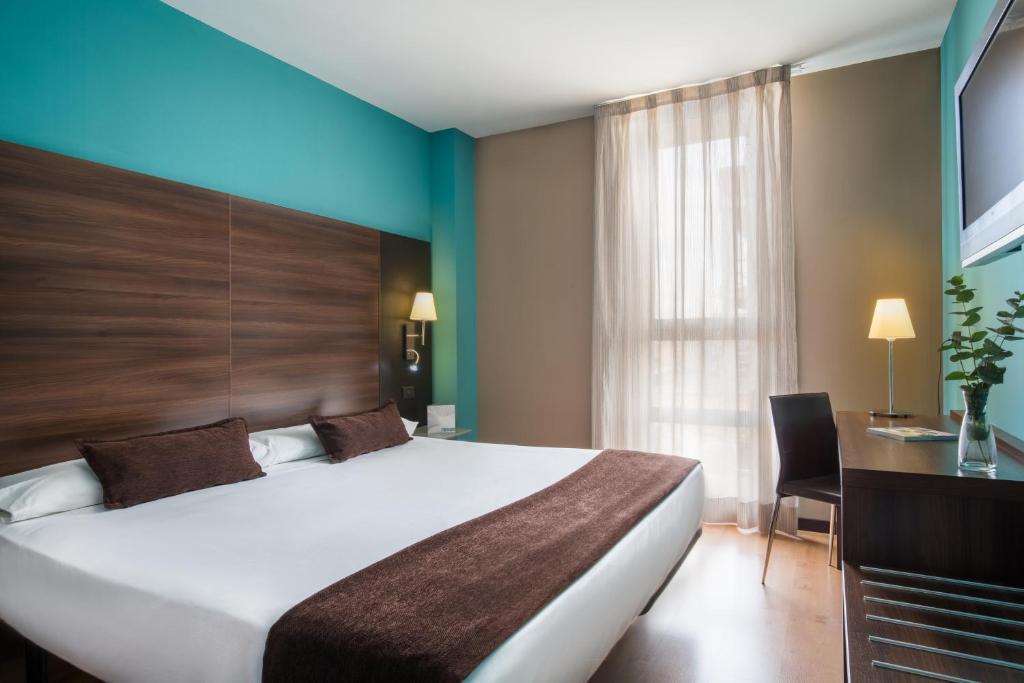 萨拉戈萨阿拉贡国王费尔南多二世水疗酒店的酒店客房设有一张大床和一张书桌。