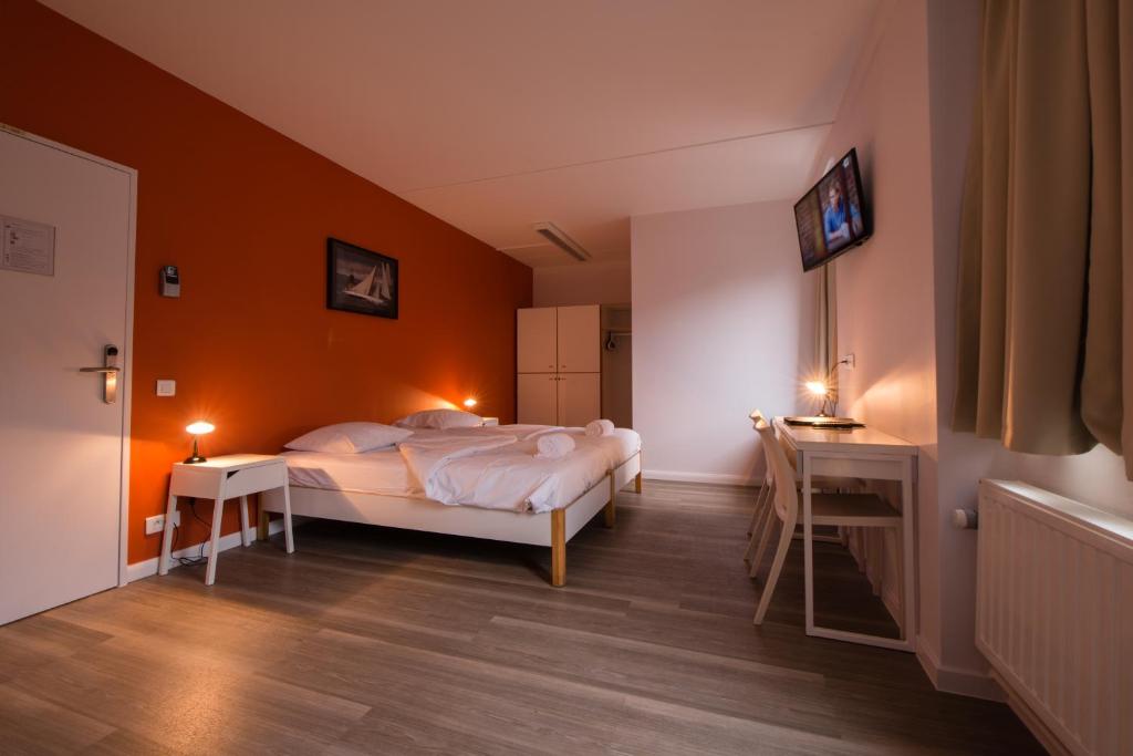 布鲁塞尔三喷泉旅馆的一间卧室配有一张橙色墙壁的床