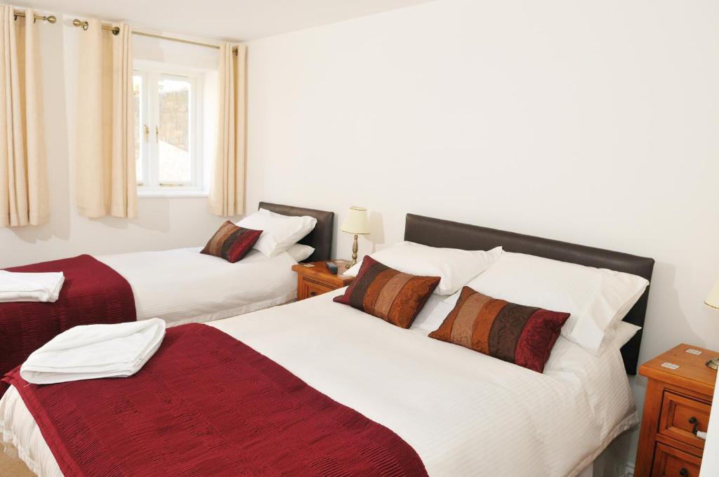 达灵顿Balmoral Guest House的一间卧室配有两张带白色和红色床单的床
