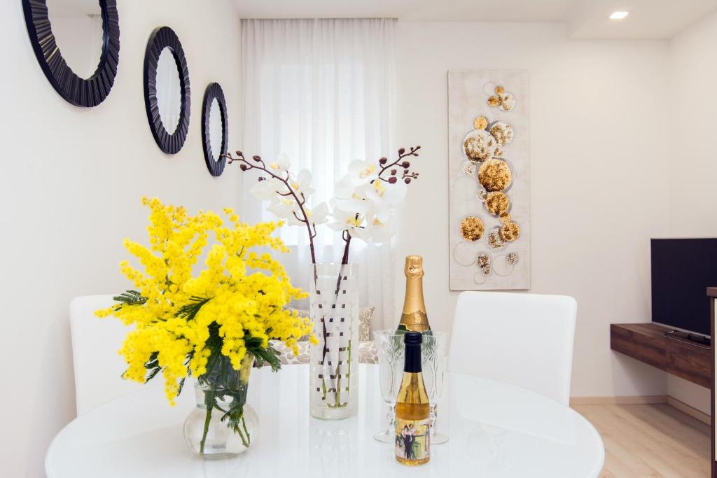扎达尔Eden Apartments的一张桌子,上面放着一瓶香槟和黄色鲜花